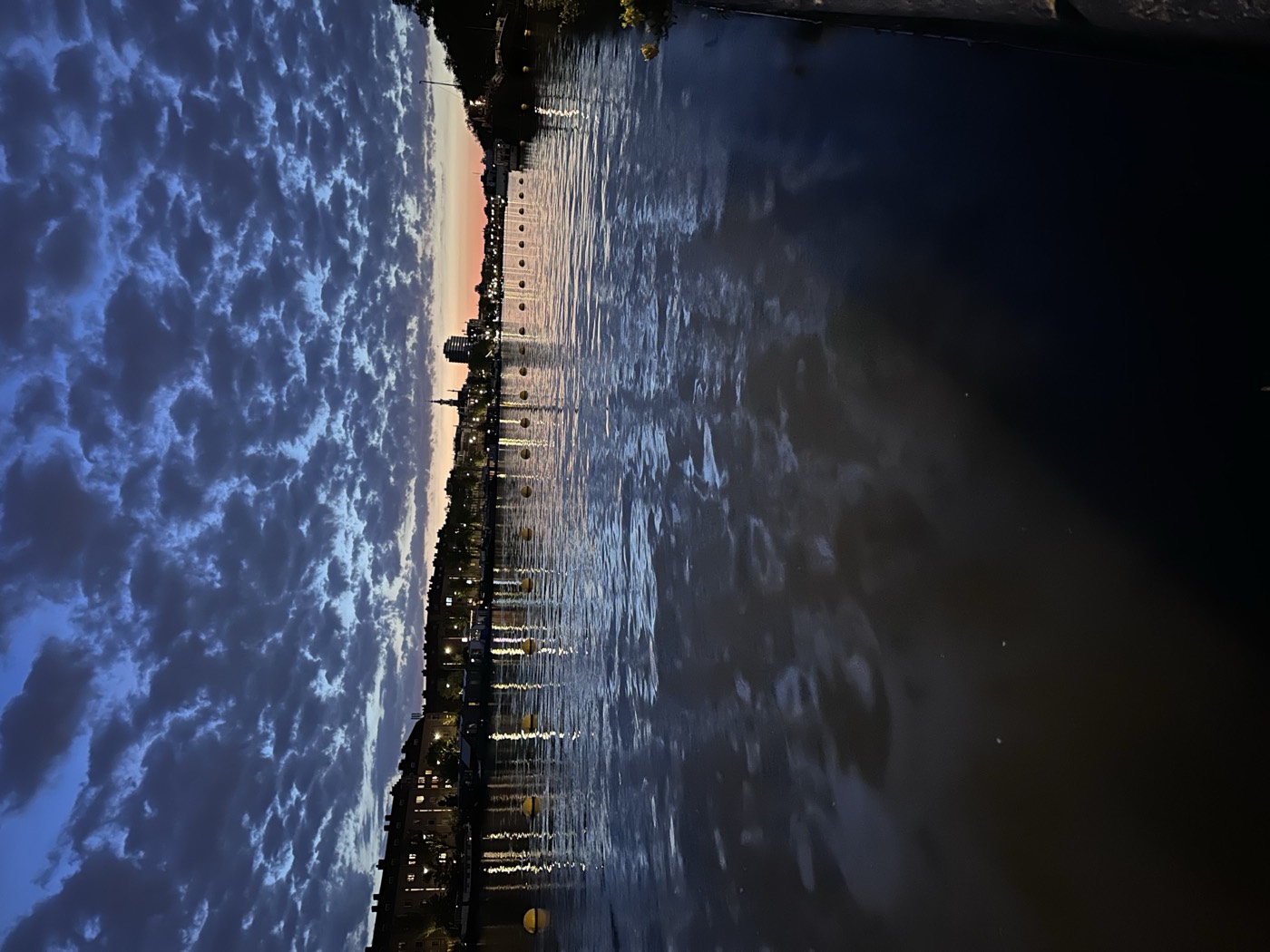 The river Amstel in Amsterdam at dusk, with the city skyline on the horizon