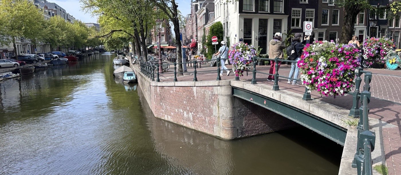 A canal bridge in central Amsterdam, its railings lined with flower baskets